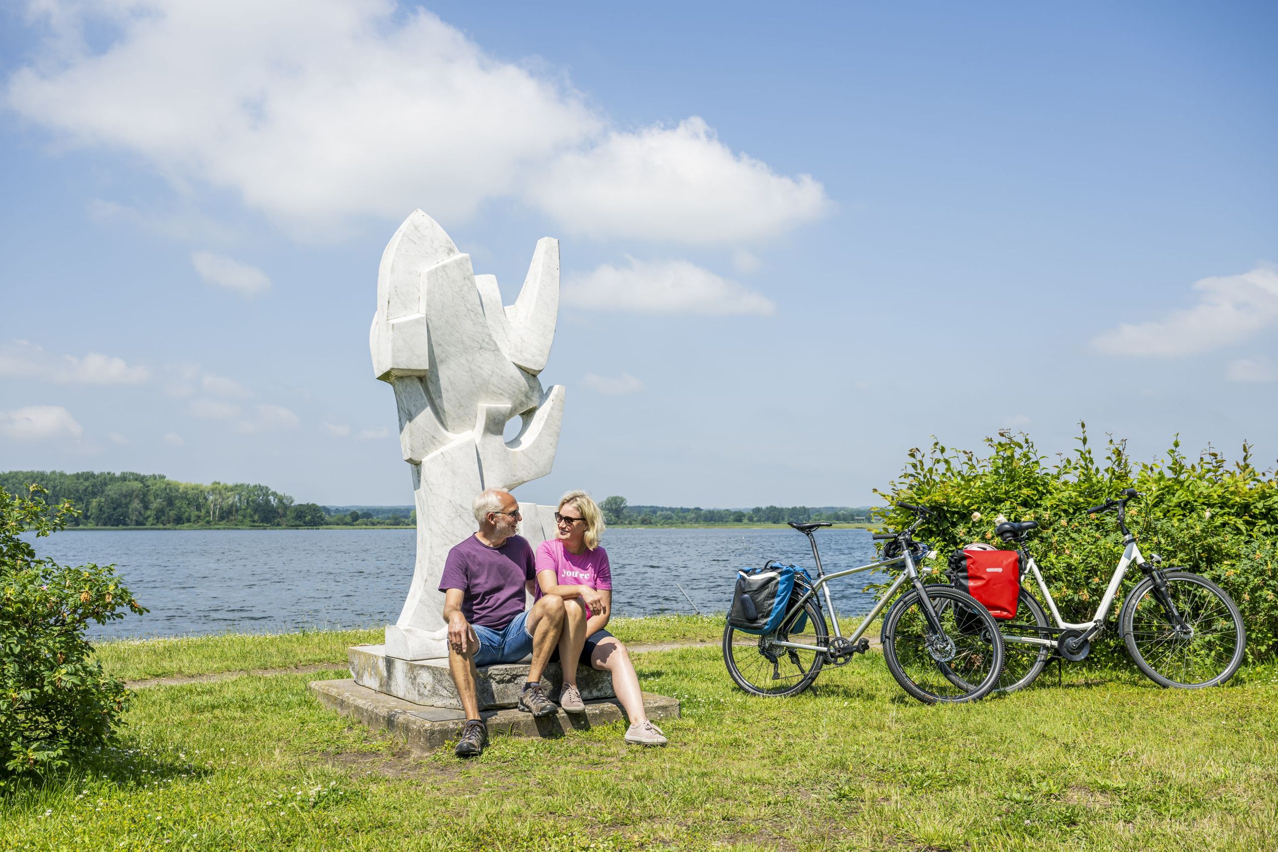 Radreisende pausieren an dem Kunstwerk Segel und Möwen