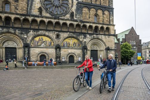 Radfahrende schieben ihr Rad vor dem St. Petri Dom