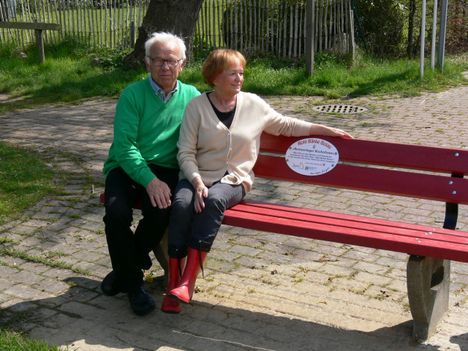 Zwei Menschen sitzen auf einer roten Bank in Bosau