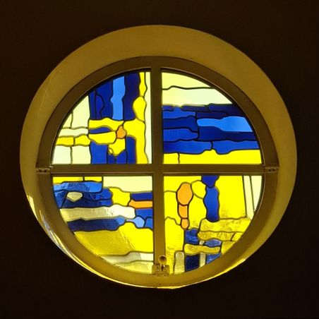 Rundes Buntglasfenster mit abstrakten blau-gelben Mustern in der Jesus Guter Hirt-Kirche in Bad Bramstedt.