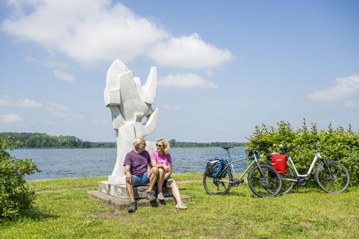 Radreisende pausieren an dem Kunstwerk Segel und Möwen