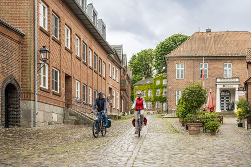 Radreisende fahren entlng des Plöner Rathauses