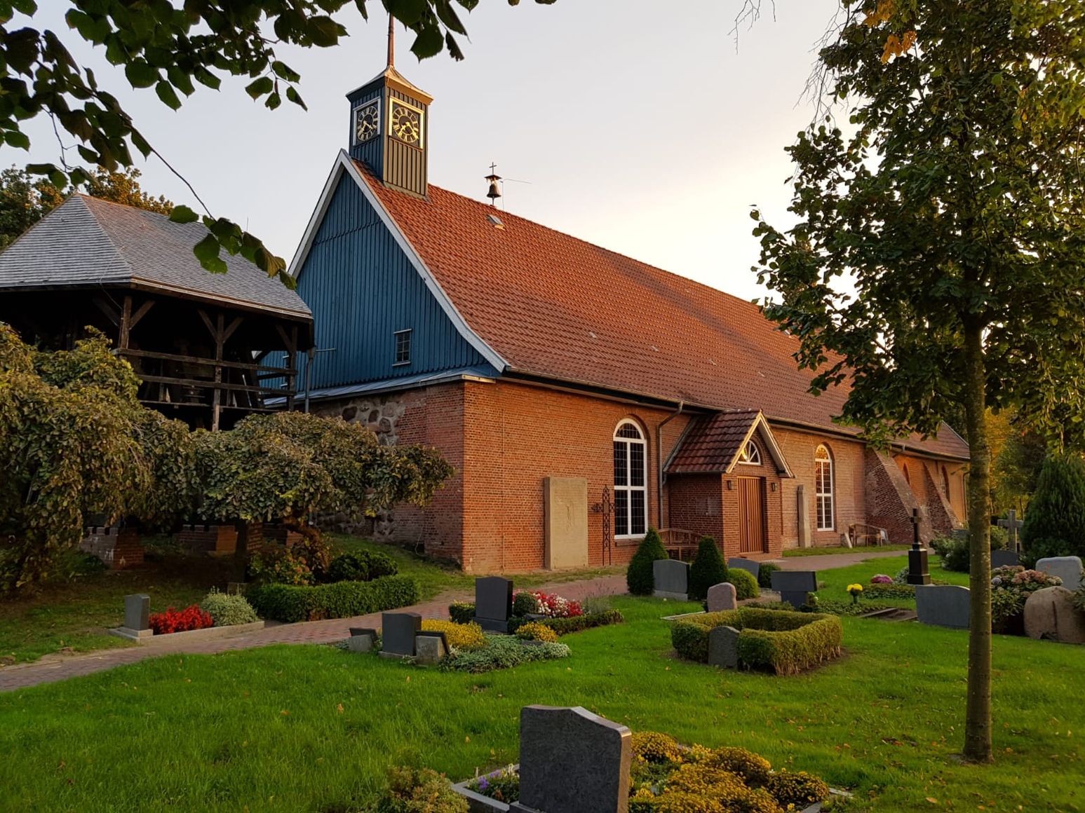 Die Kirche St. Marien in Heiligenstedten, umgeben von einem gepflegten Friedhof mit Grabsteinen und Bäumen.