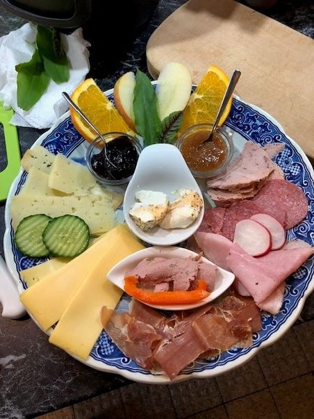 Frühstücksteller mit Käse, Aufschnitt, Obst und Aufstrichen.