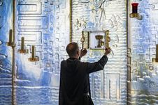 Ein Mönch des Kloster Nütschaus steht an der Altarwand und holt einen Krug raus