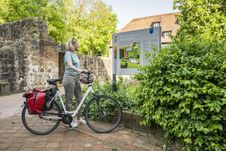Frau mit Rad steht vor einer Infotafel im Klosterpark