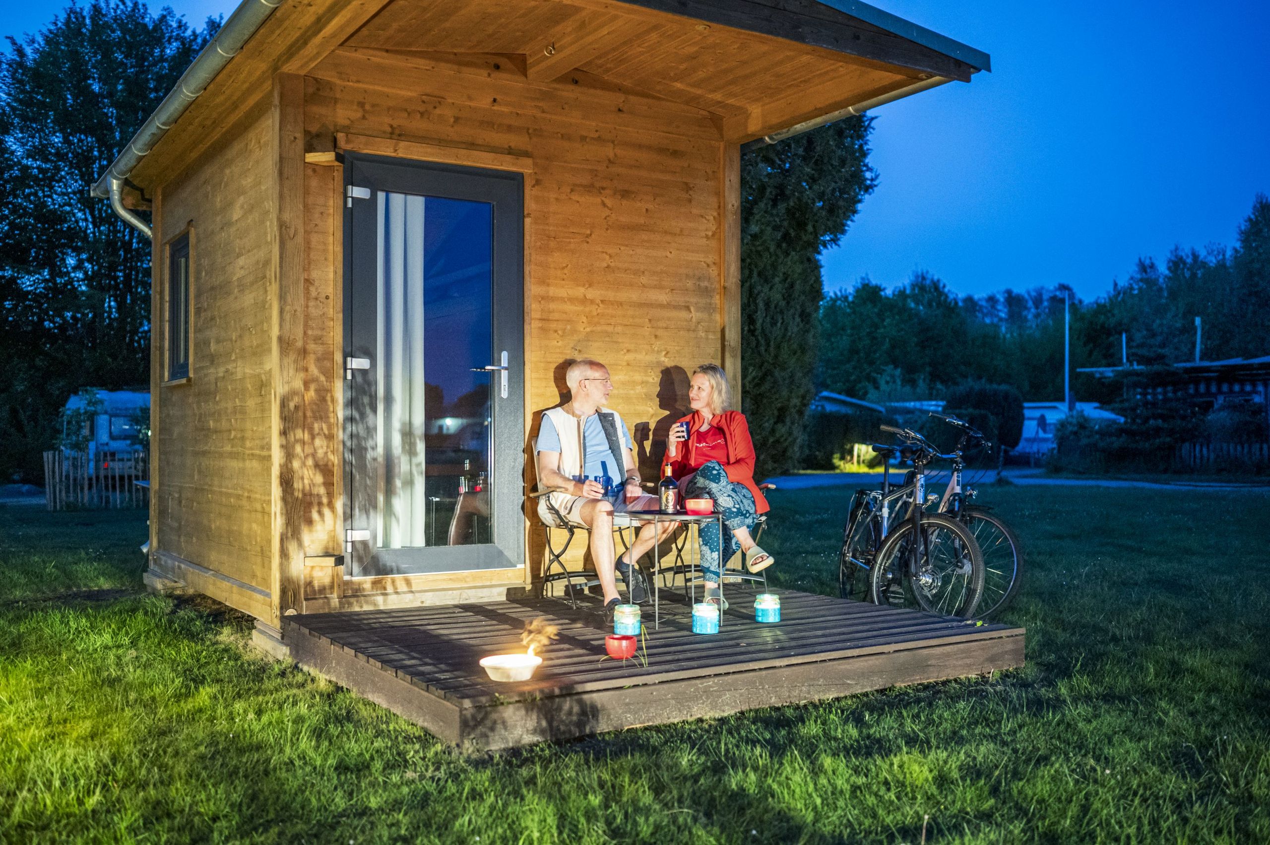 Paar sitzt am Abend vor Tiny-House auf dem Campingsplatz Sonnenkamp