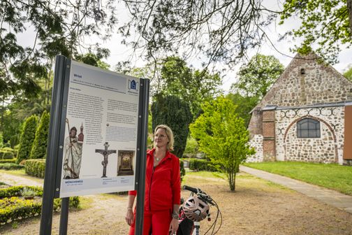 Radreisende steht vor einem Infoschild an der Kirche zu Stellau
