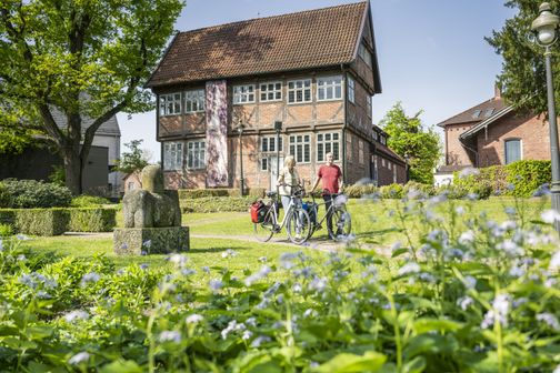Radreisendes Paar schiebt Fahrräder im Skulpturenpark des Königin-Chrstinen-Haus