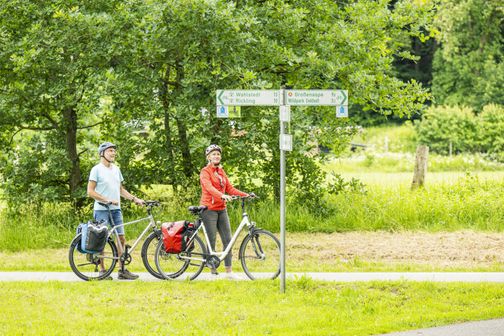 Radreisende orientieren sich an Wegweisern auf dem Mönchsweg im Segeberger Forst