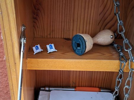 Ein Regal mit einem Stempel, zwei Pins und einem Stift. Eine Kette ist am Stempel befestigt.