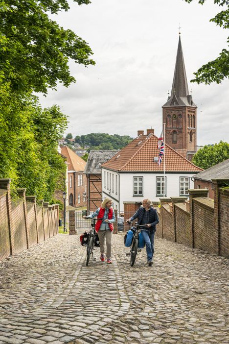 Radreisende gehen Richtung Plöner Schloss